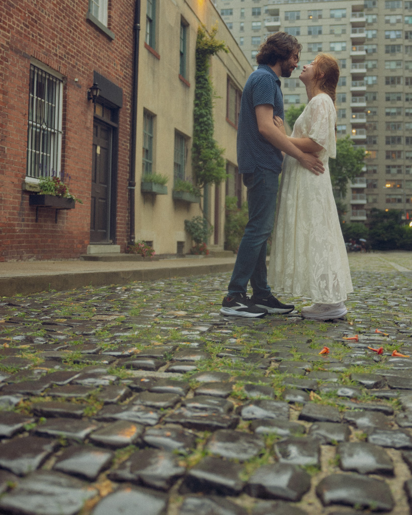 Romantic NYC couple photoshoot capturing a sweet kiss on the cobblestones of Washington Mews